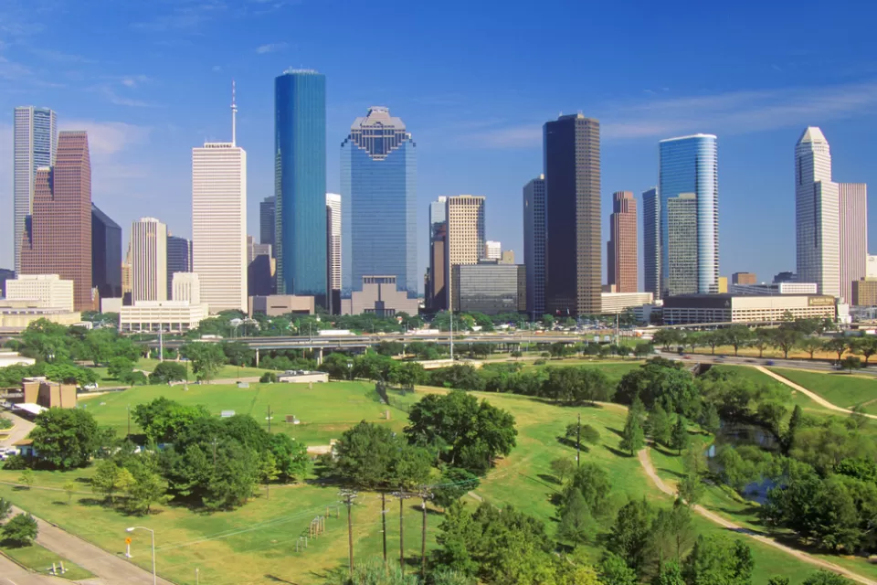 Aerial view of green Memorial Park lawns and trees with downtown Houston skyline in background